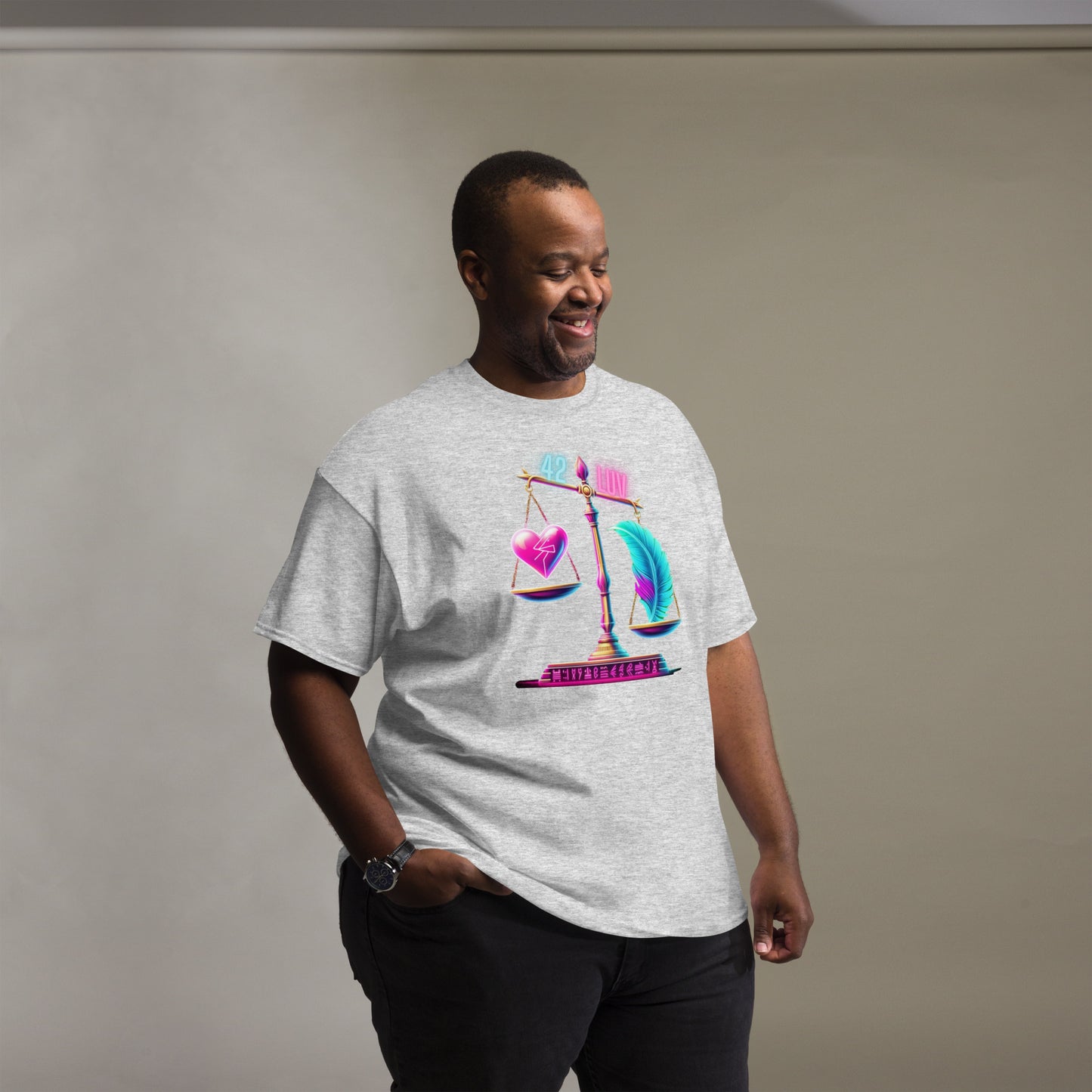 Fashionable Black Man Wearing a Light Grey T-Shirt with a Heart and Feather Scale Design, Inspired by Ma'at – Showcasing Trendy Urban Fashion for Men with Symbolic Art Representing Balance and Justice, Captured in a Studio Setting